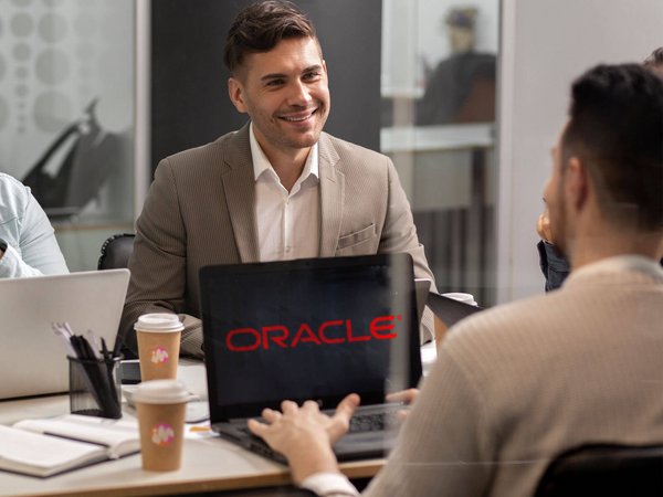 Two men smiling and talking, Oracle logo